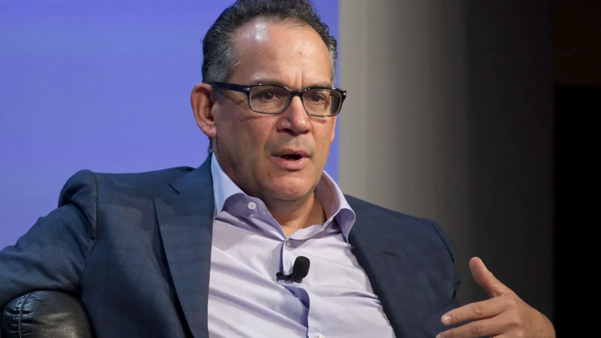 A person wearing glasses gestures while speaking.