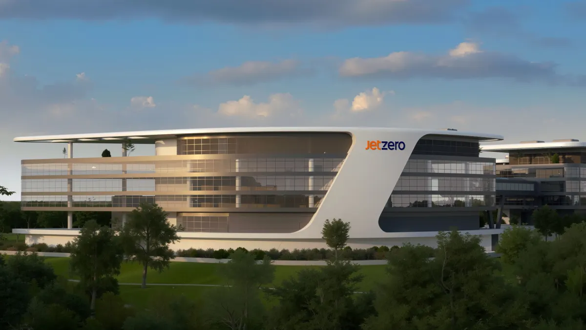 A white building with rows of glass windows and the orange and purple JetZero sign on it.