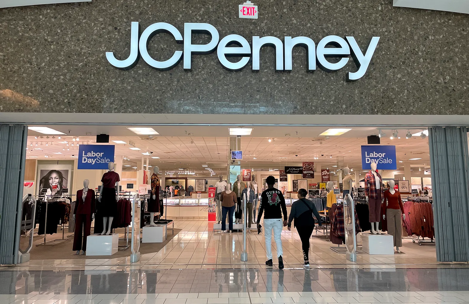 Two people walk into a J.C. Penney retail store.