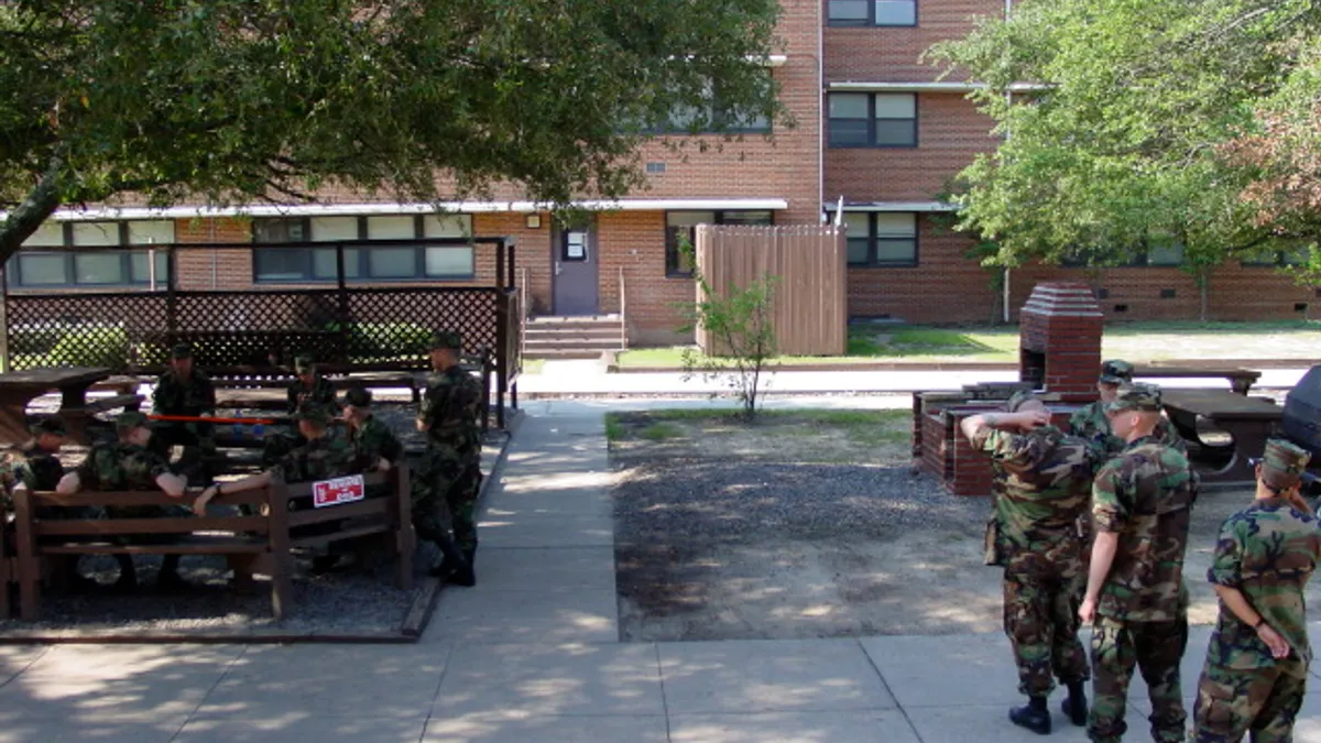 A view of army recruits undergoing training at a school in Fort Gordon, Georgia on a hot summer day, with trees in the background.