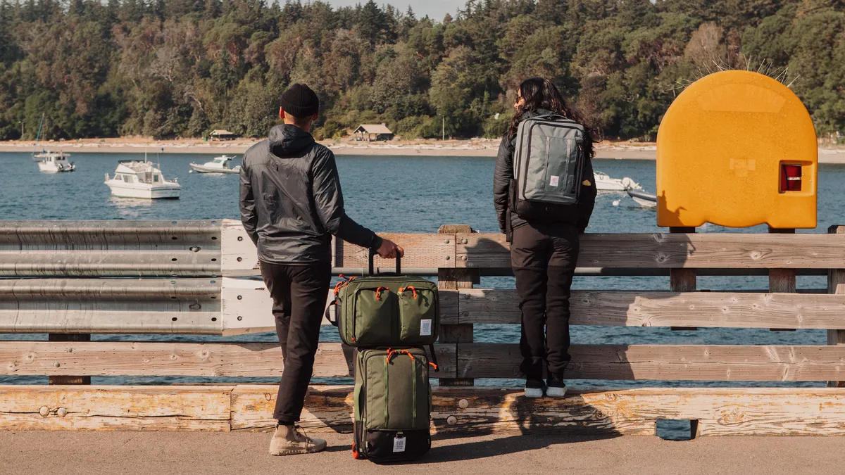 Two people standing with Topo Design luggage products.