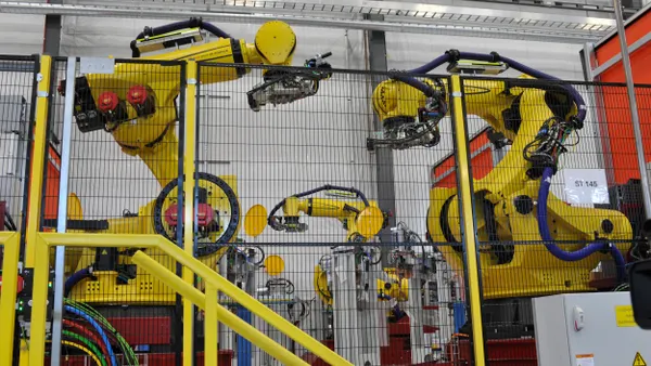 Industrial robots behind a mesh screen.