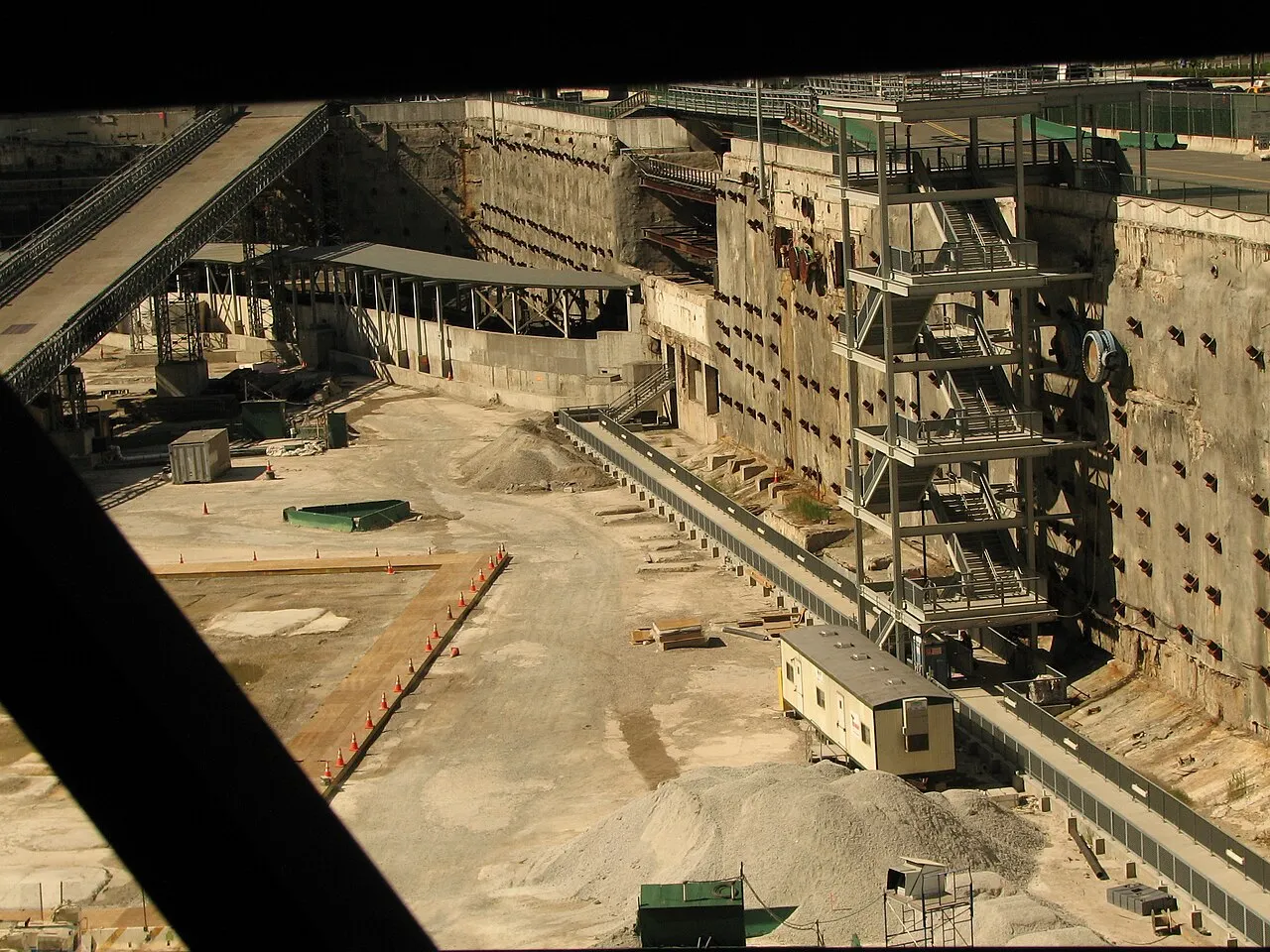 A downward view of a large, walled excavation in a major city.