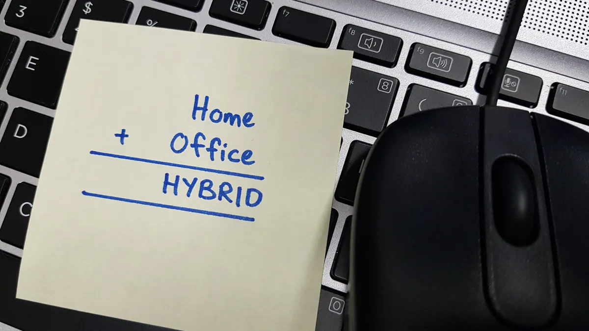 A sticky pad note on computer keyboard with the words Home, Office and Hybrid written on it