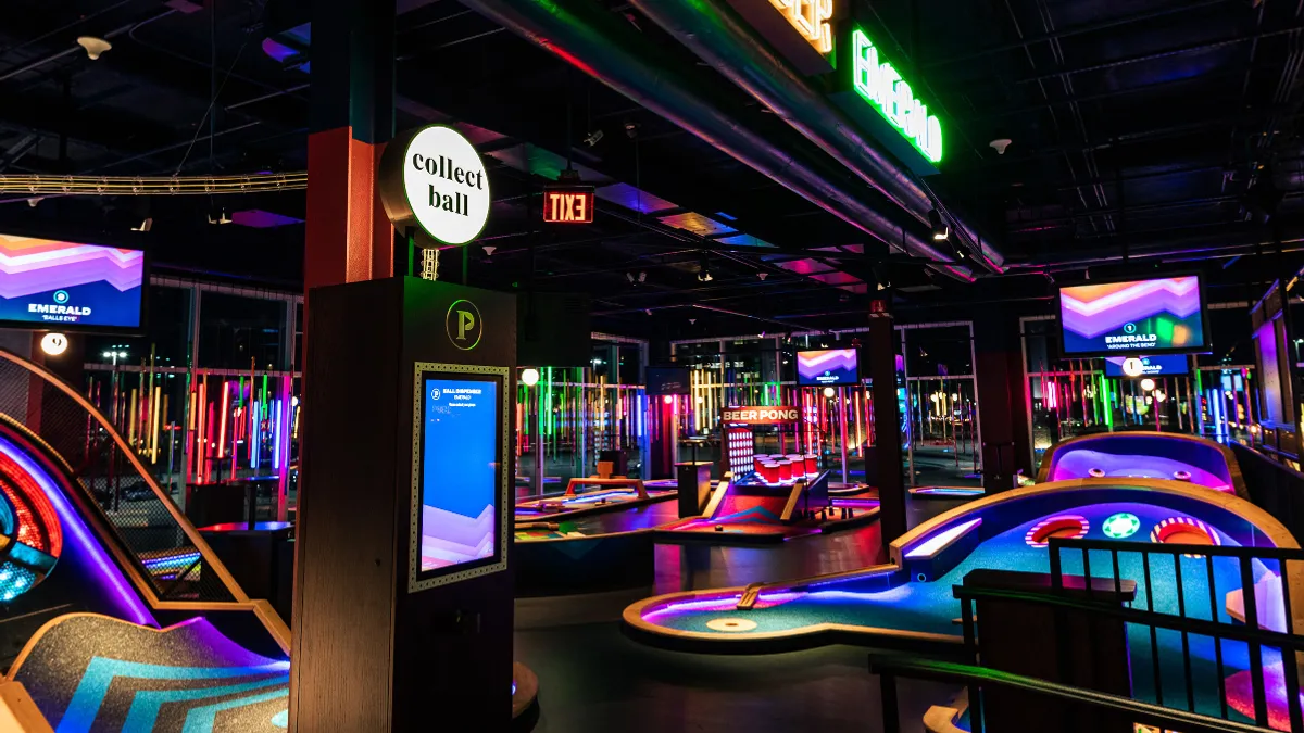 An image of an indoor mini golf course with neon lighting