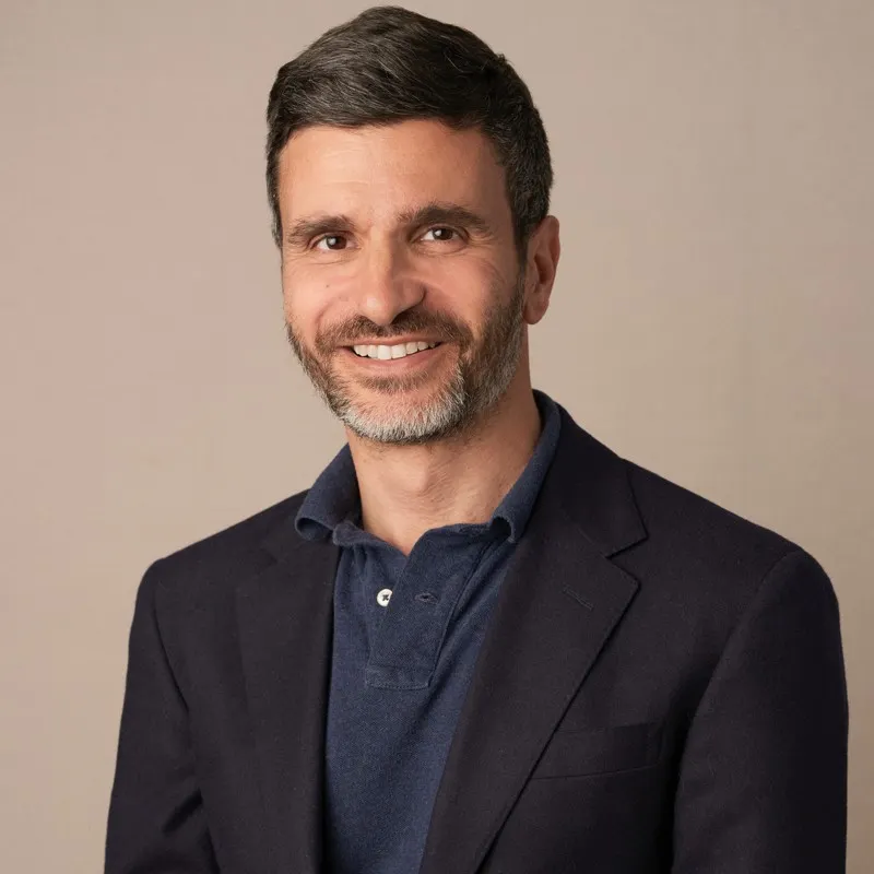 A person with a beard and mustache wears a black jacket.
