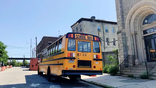 A view of the back of a yellow school bus parked on the street.