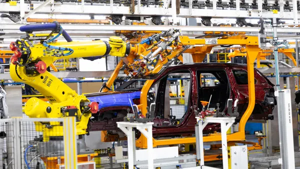 A yellow-painted robot moves the windshield into position on a Jeep Grand Cherokee at the Detroit Assembly Complex – Jefferson in Michigan.