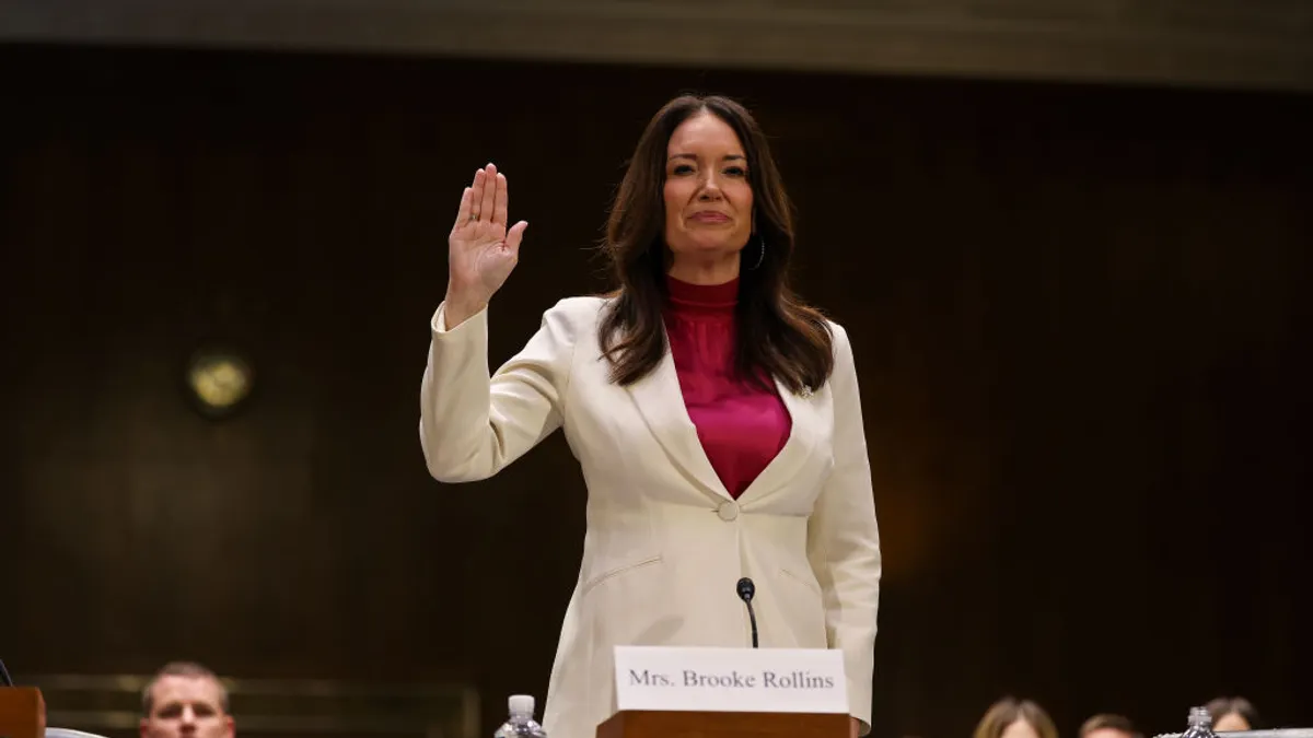 Brooke Rollins stands with her hand raised