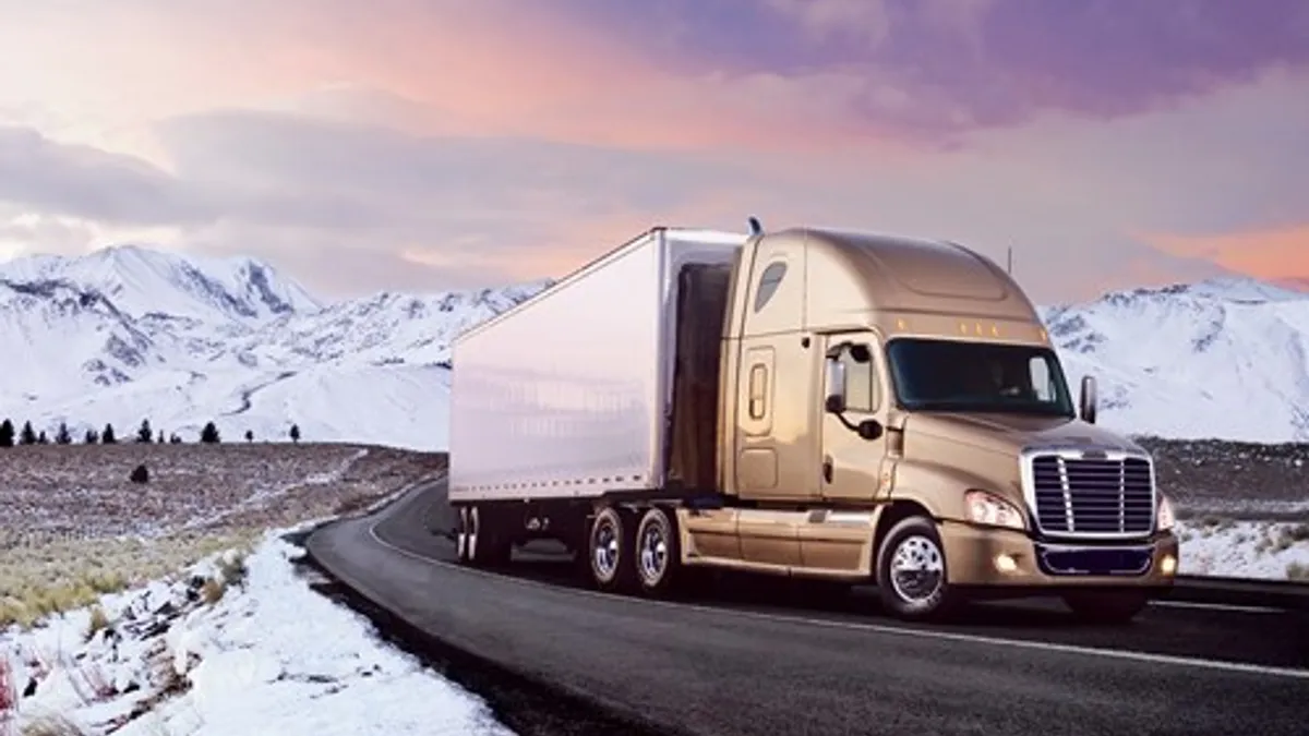 A Freightliner Cascadia on a road with snowyy mountains in the background.