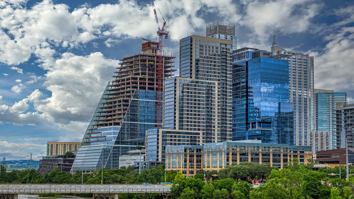 Skyline view of several shiny glass office buildings, one of which is still partly composed of scaffolding.