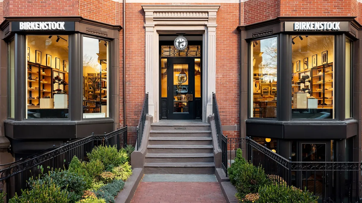 A brick building displays two windows with "Birkenstock" above them and a front door.