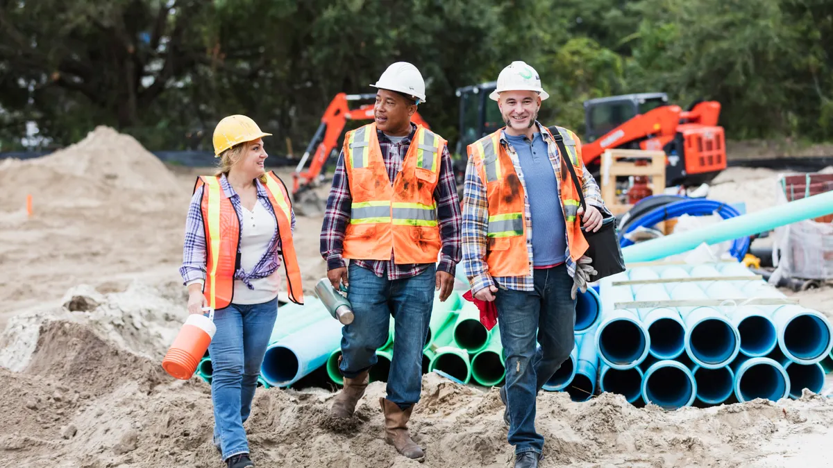 Three diverse construction workers walk on a jobsite.