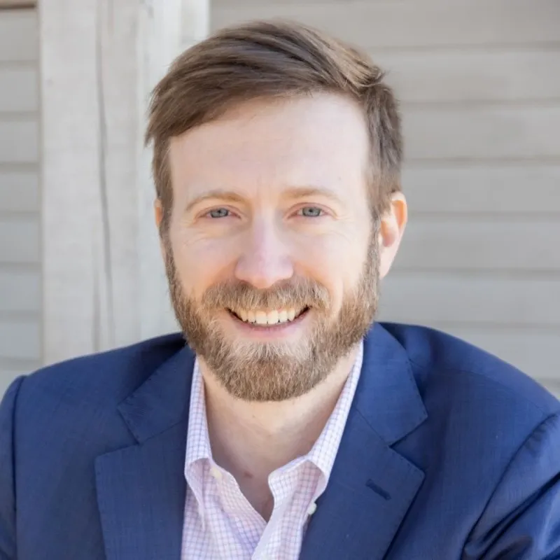 Patrick Velliky smiles into the camera wearing a blue suit.