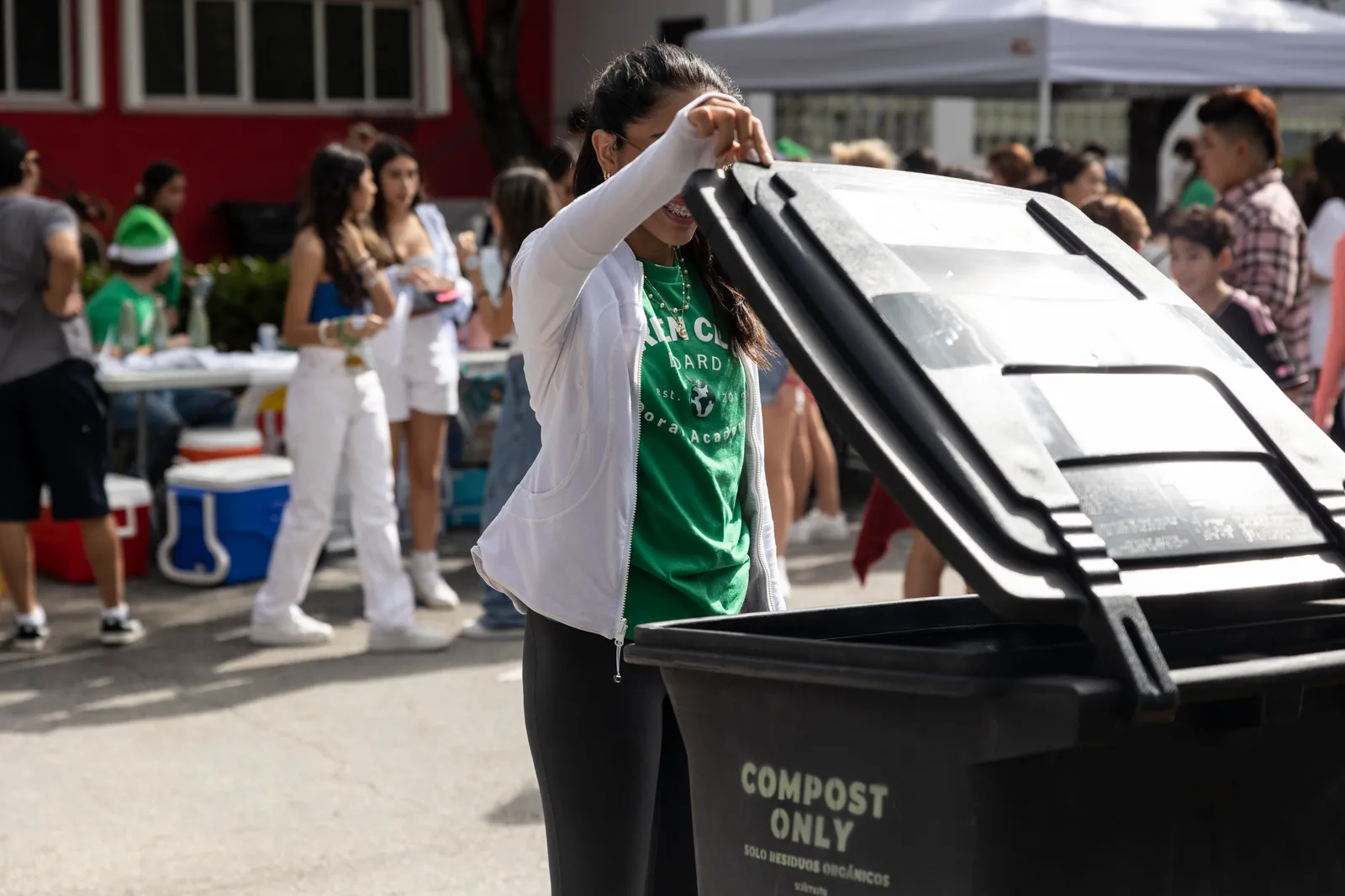 A person lifts the lid of a compost container in Florida