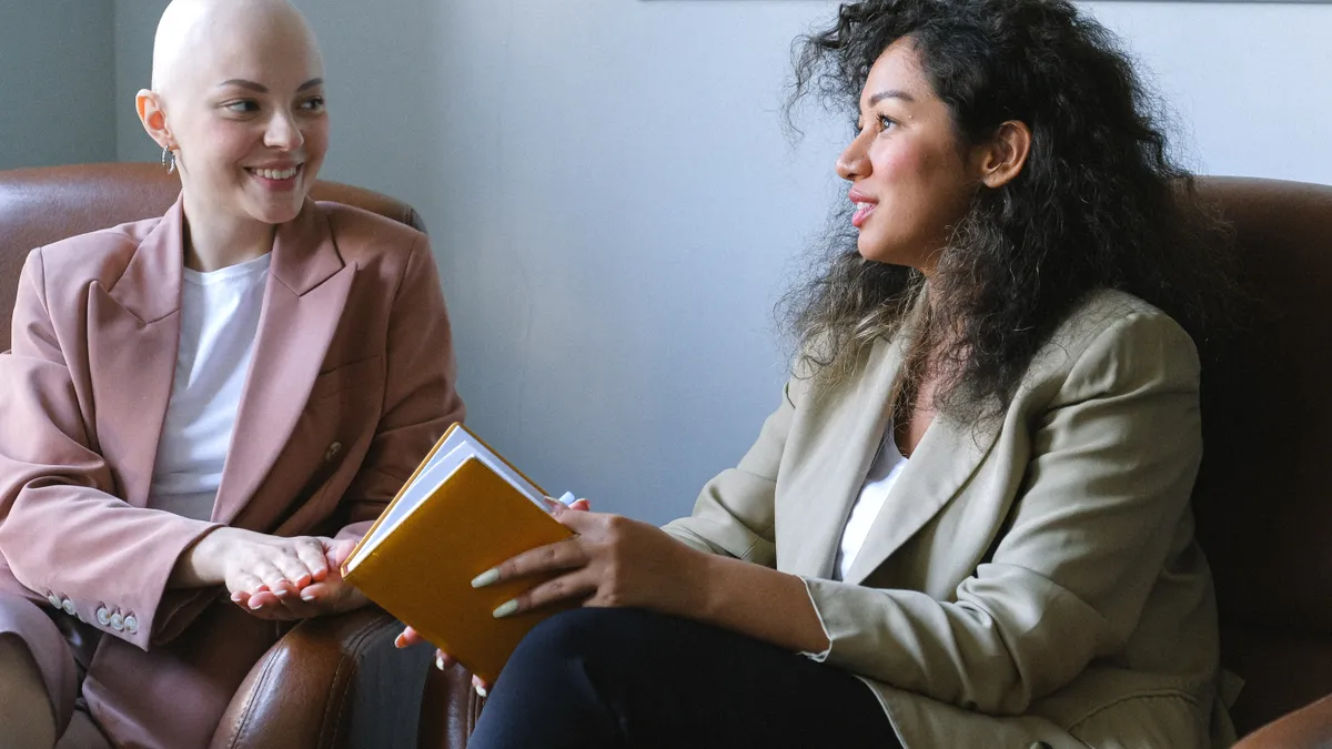 Two feminine-presenting people are talking in an office