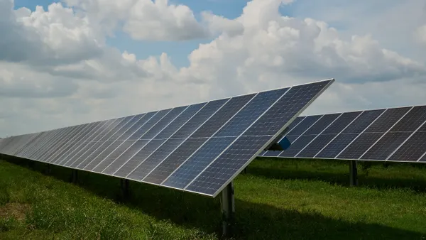 Rows of solar panels in a grassy field.
