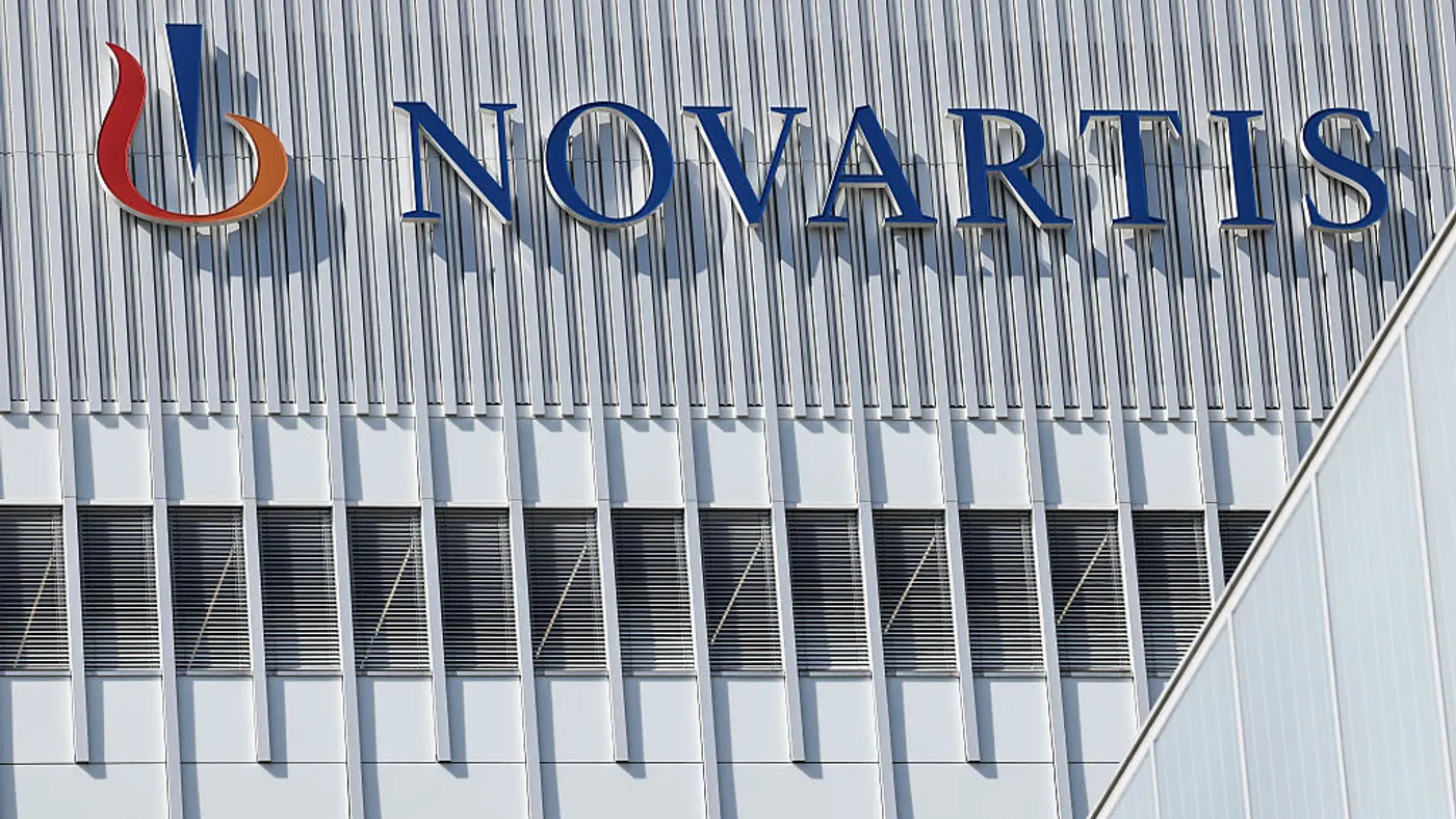 A sign spelling Novartis hangs on the side of a building.