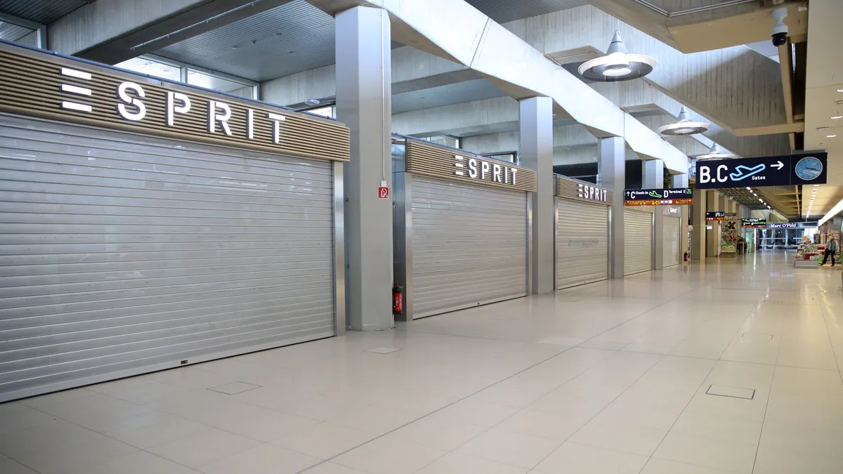 A line of Esprit stores in an airport terminal have closed steel gates.