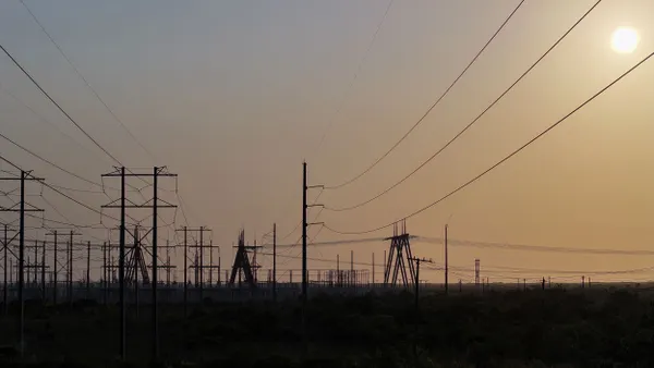 High voltage power lines seen in silhouette at sunset