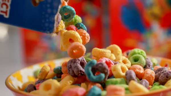 Froot Loops are being poured into a cereal bowl