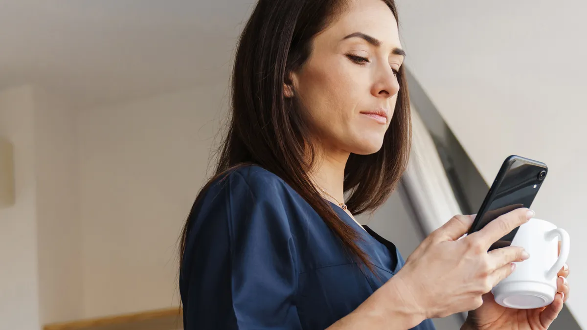 Women checking smartphone while drinking coffee