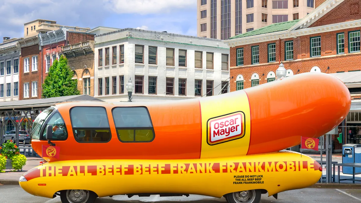 A side profile shot of Oscar Mayer's Frankmobile, a rebranded version of the Wienermobile, sitting in a parking lot