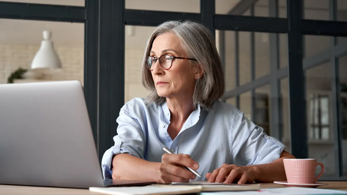 Women with pen in her hand working on laptop