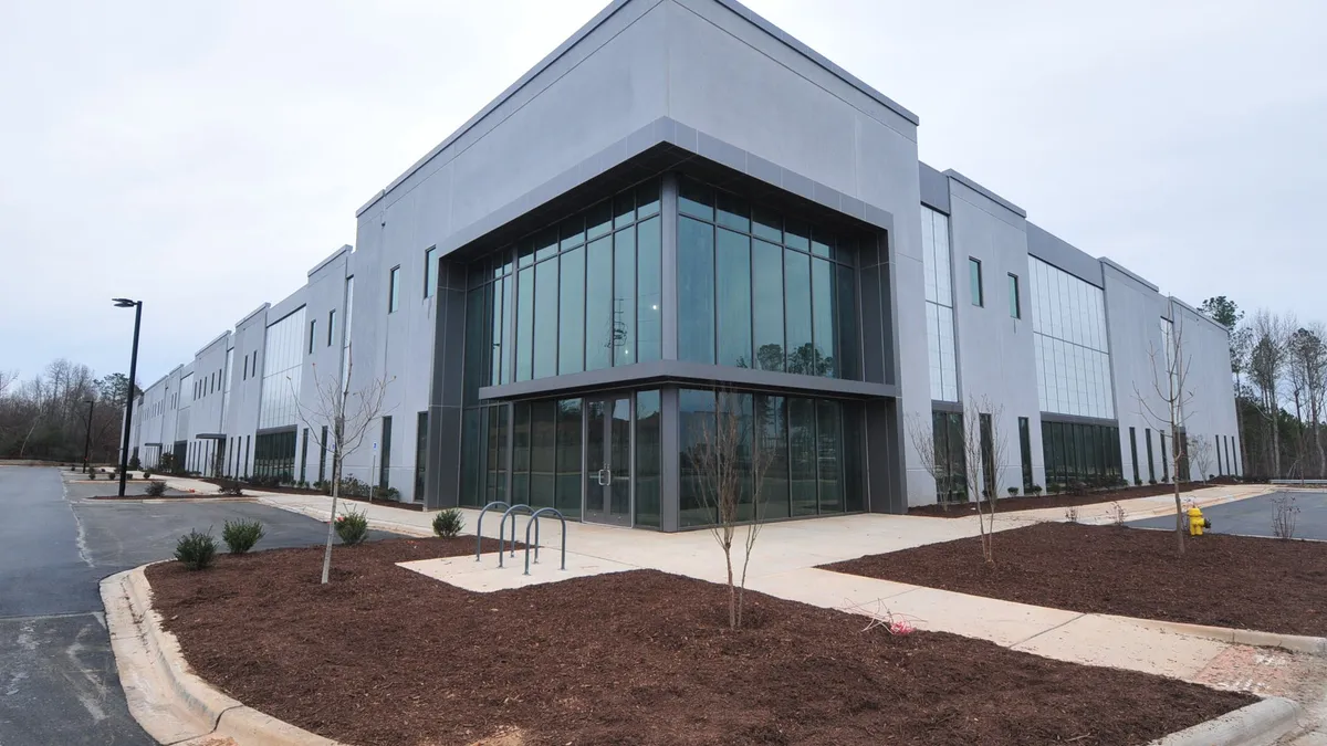 A large, square building surrounded by a sidewalk and landscaping.