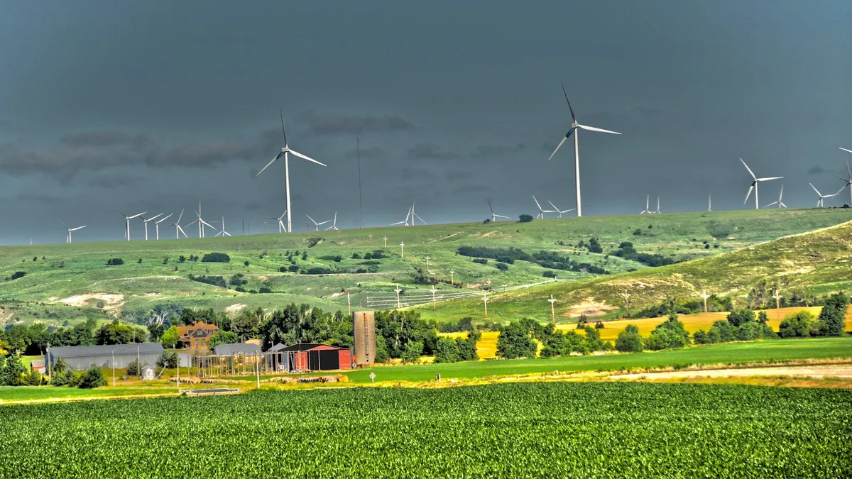 A farm with wind turbines in the background.