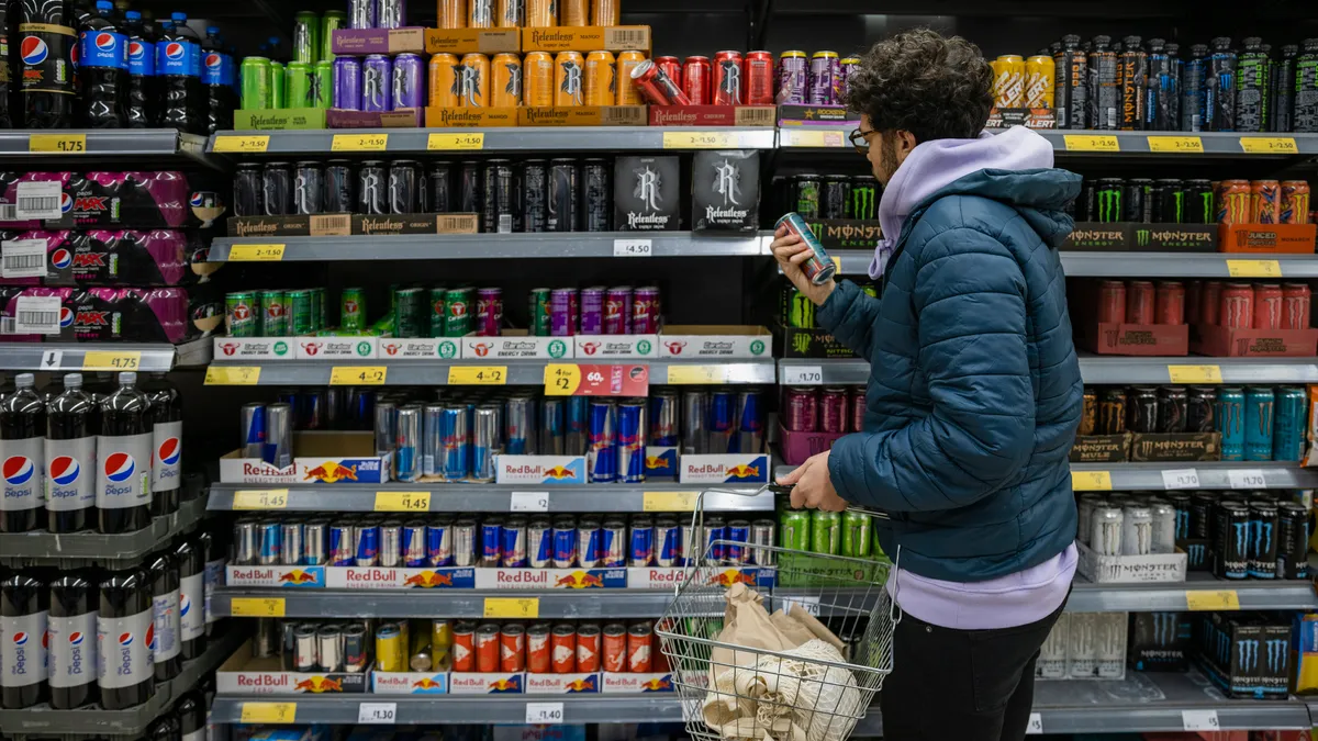 A man browses shelves of beverages at a supermarket