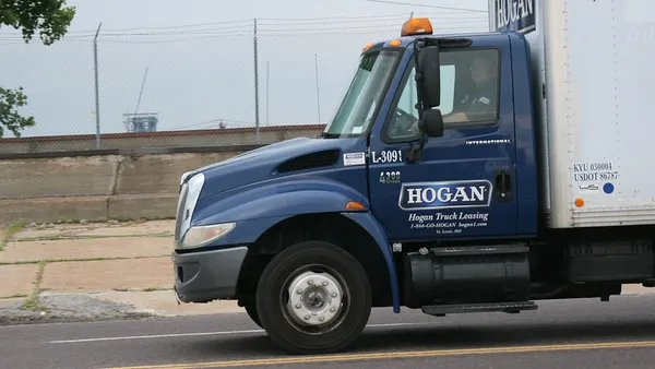 A Hogan truck on the roadway with a driver inside the vehicle.