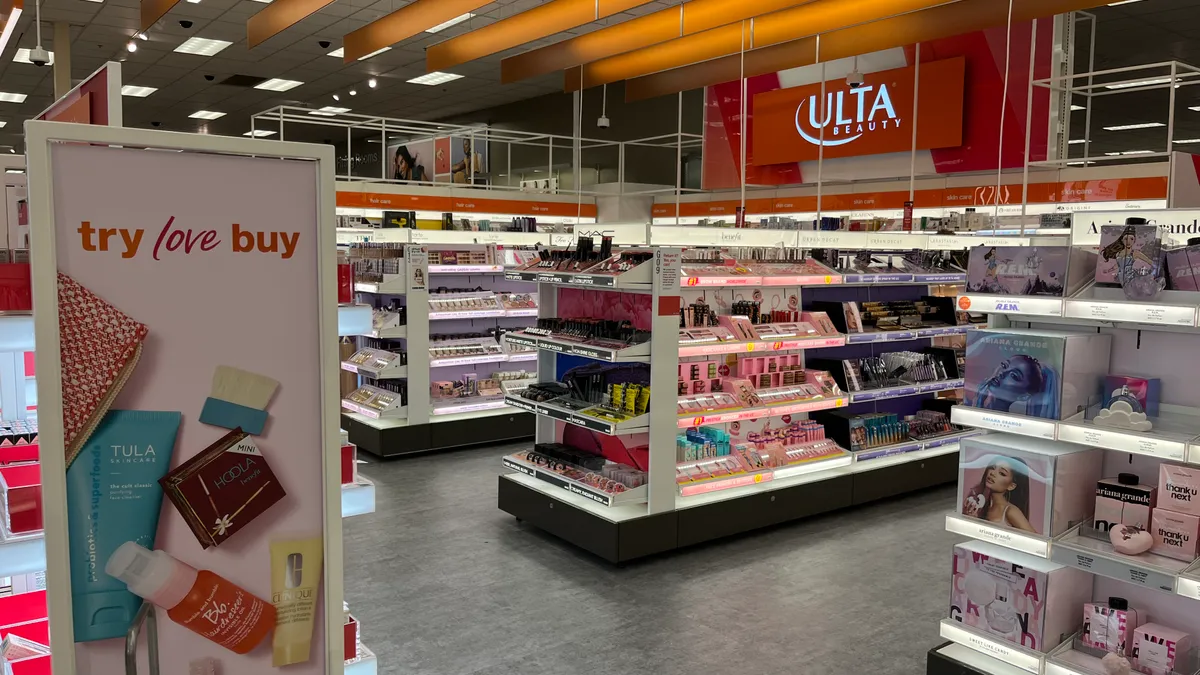 A sign that reads "try love buy" in front of a range of beauty displays at an Ulta Beauty shop-in-shop inside of a Target.