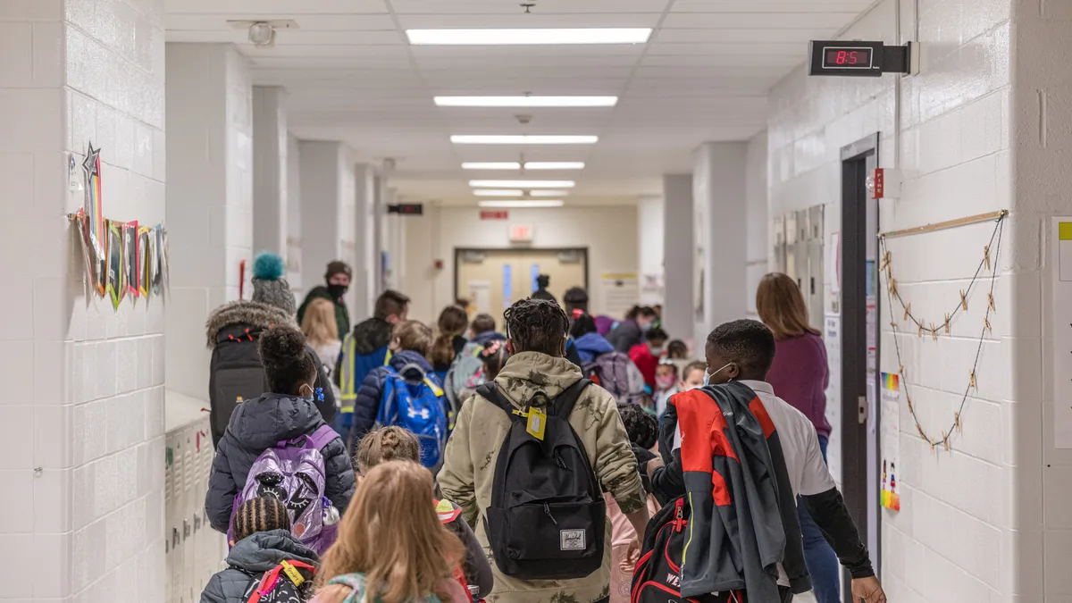 Students walk in an elementary school hallway.