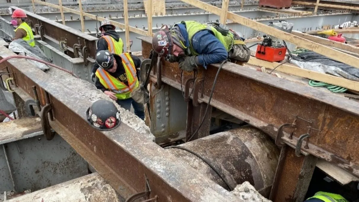 Construction workers work on a section of the Lemoine Avenue bridge