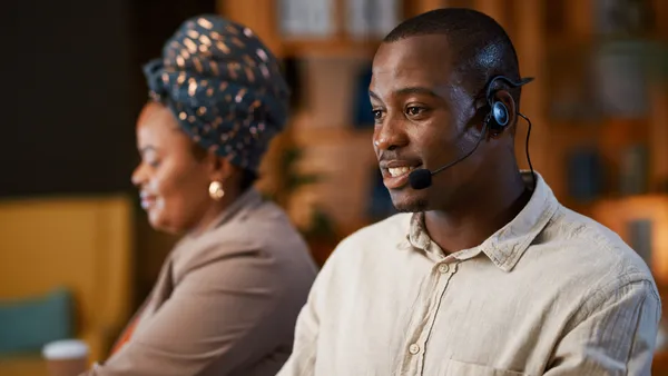 Two contact center agents talk on headsets.