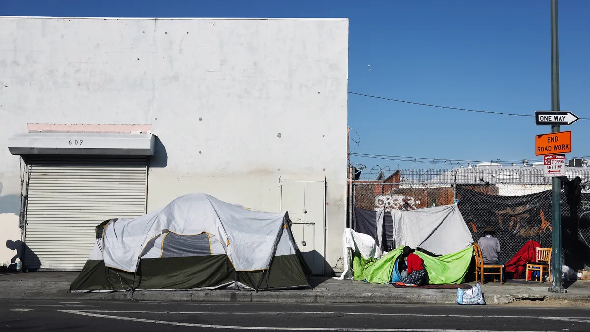 A white and green tent in front of a white building on a sunny day.