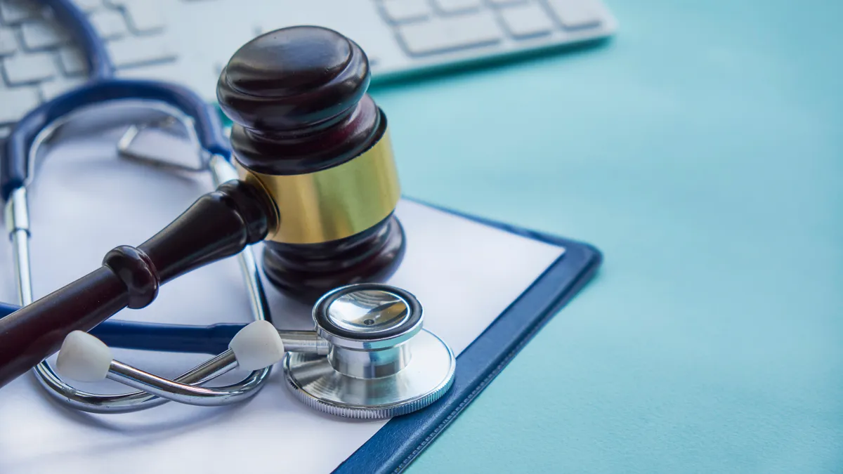 A gavel rests on a pile of money wrapped with a stethoscope.