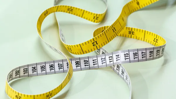 A curled measuring tape lies against a beige background.