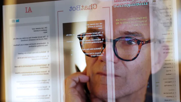 Close up image of a man studying a see-through computer monitor that’s displaying text provided by an chatbot.