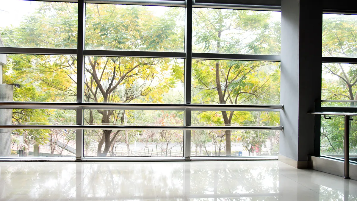 An atrium in a modern, healthy building with trees outside the window.