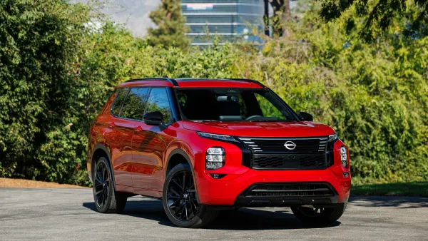 A red, 2026 Nissan Rogue plug-in hybrid SUV parked outdoors on a sunny day.