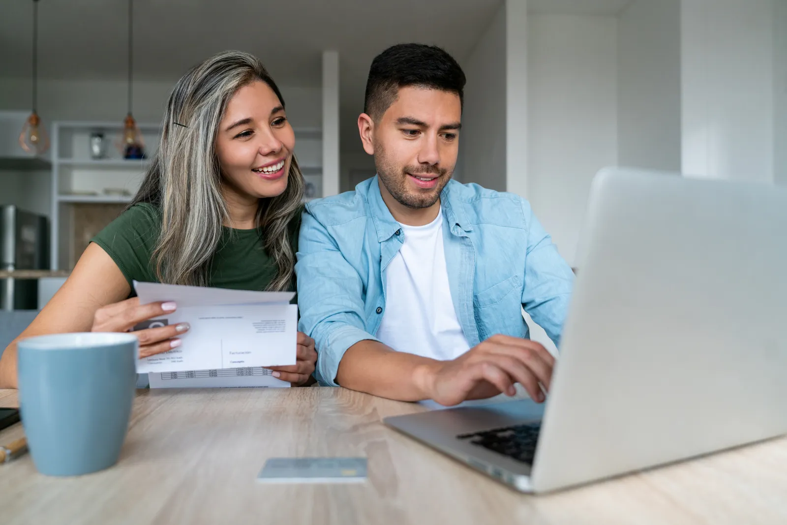 two young people pay bills on a computer