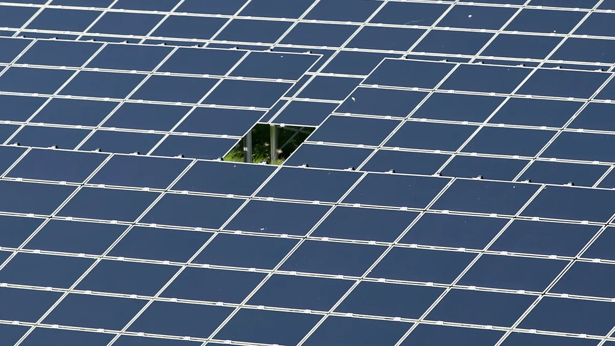 An array of photovoltaic solar panels with one missing from the center.