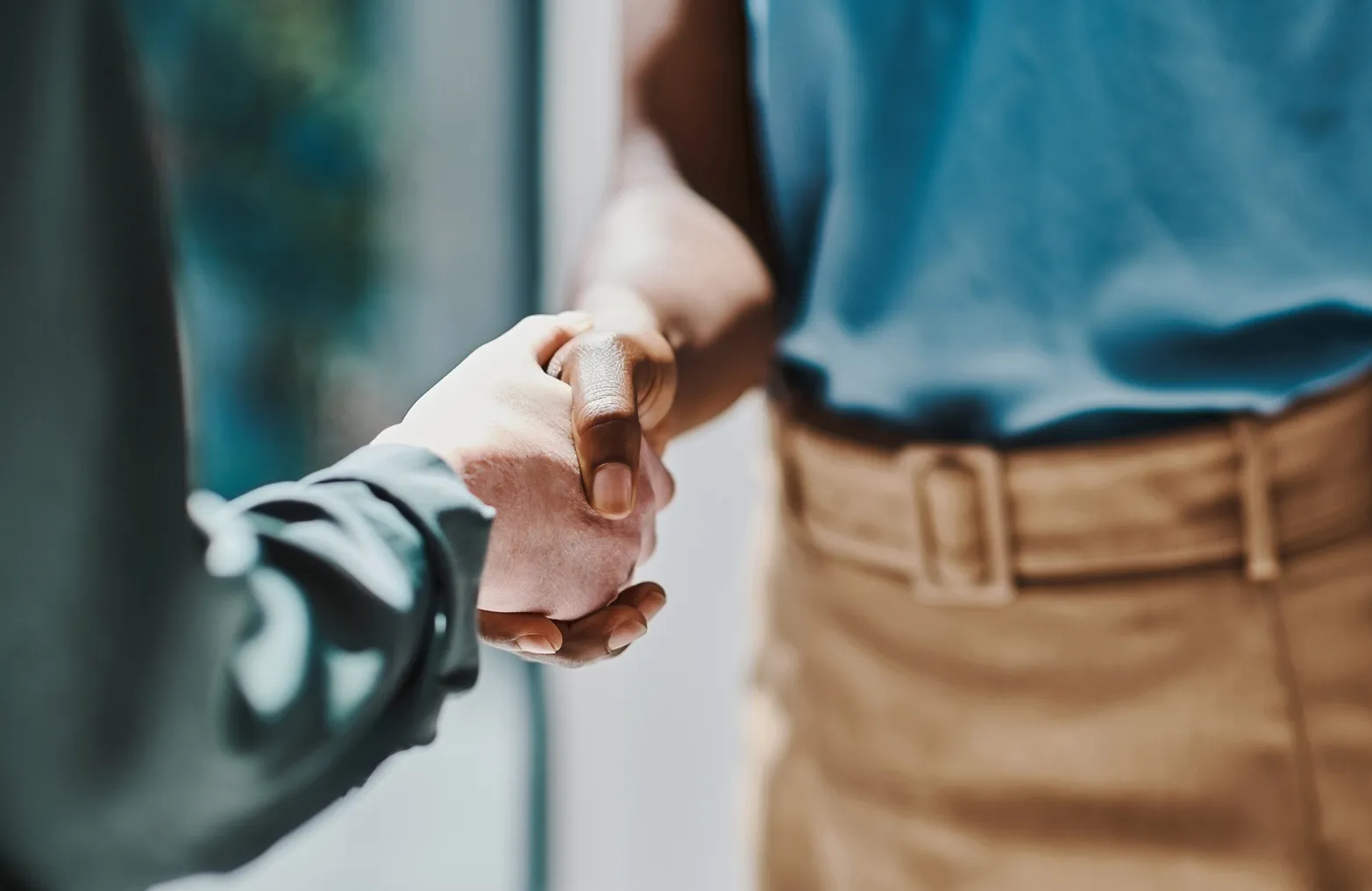 A White hand and a Black hand shake in the office