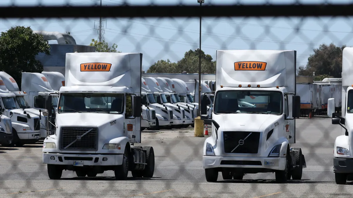 Yellow Corp. trucks sit at a company facility behind a fence in 2023.