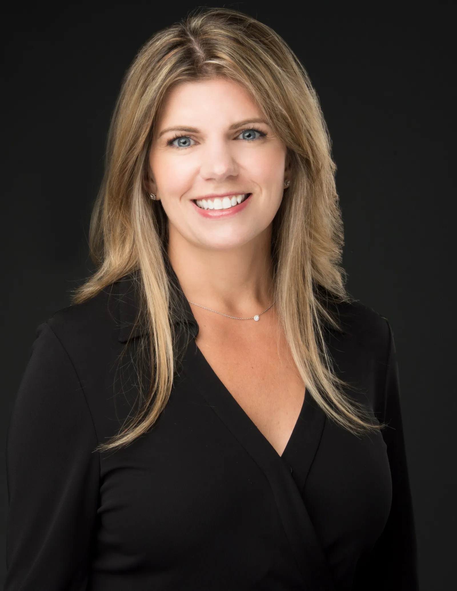 A smiling white woman with blond hair and a black shirt.