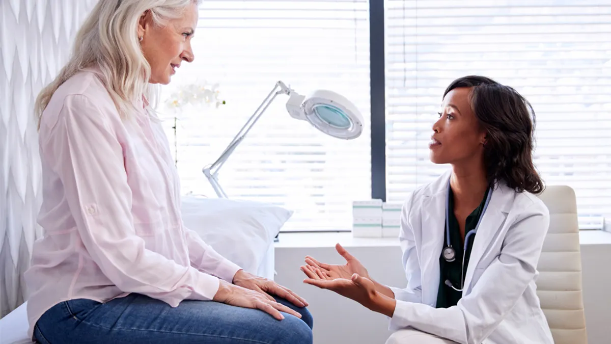 Mature woman in consultation with female doctor sitting on examination couch in office