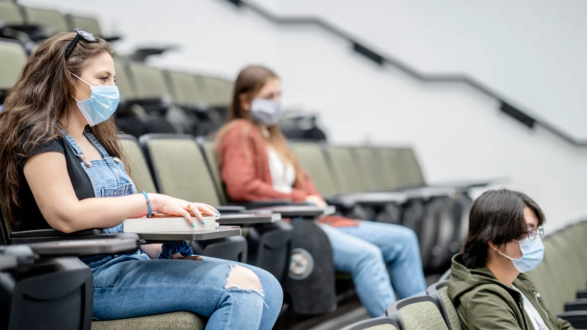 Students sitting in a lecture hall wearing facemasks.