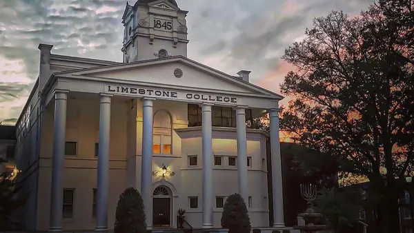 A white building with columns against the sunset.